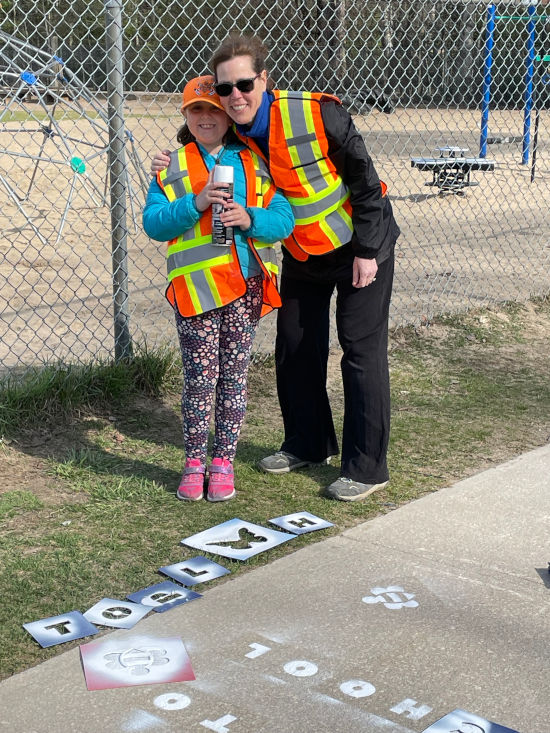 an adult and student using stencils for sidewalk painting